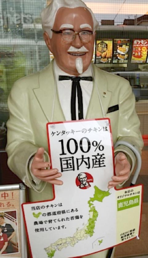 Life-size KFC Colonel statue holding Japanese sign