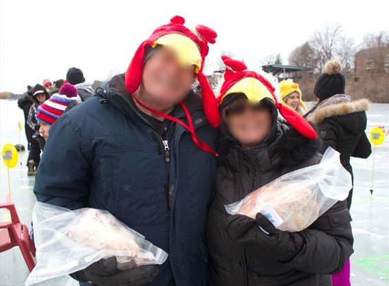 Couple standing on ice holding frozen chickens.