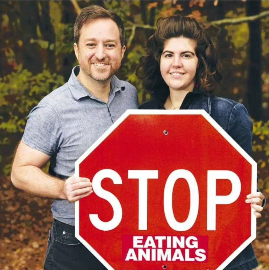 John and Juliana holding a stop sign with the words 'eating animals' added after 'stop'